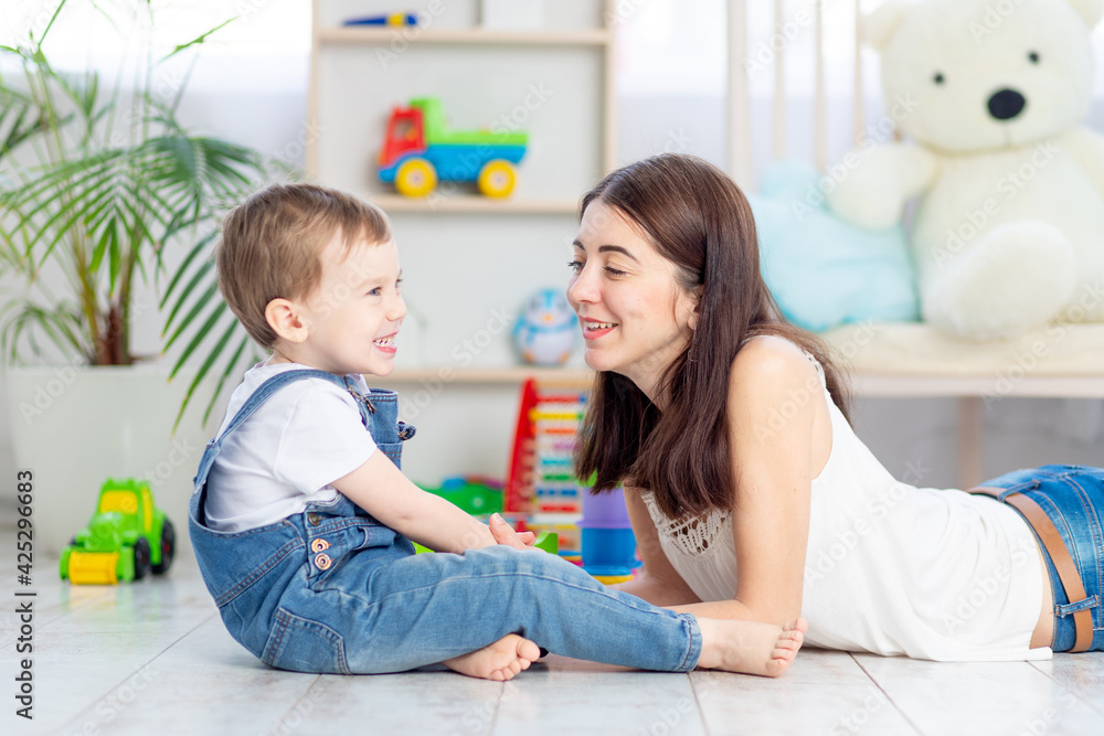 the mother talks to the baby boy or plays at home with educational toys in the children's room. A happy, loving family. the mother talks to the baby boy or plays at home with educational toys in the children's room. A happy, loving family.