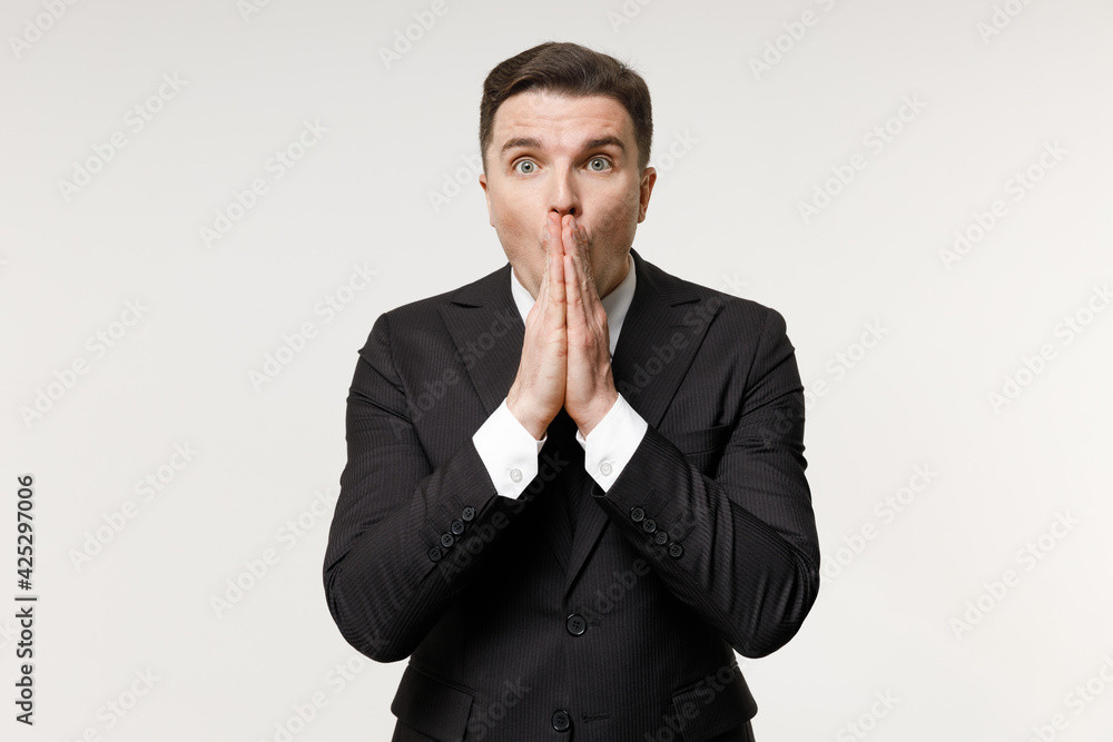 Young shocked confused employee business corporate lawyer man 20s in classic formal black grey suit shirt tie work in office cover mouth with hands palms isolated on white background studio portrait. Young shocked confused employee business corporate lawyer man 20s in classic formal black grey suit shirt tie work in office cover mouth with hands palms isolated on white background studio portrait.