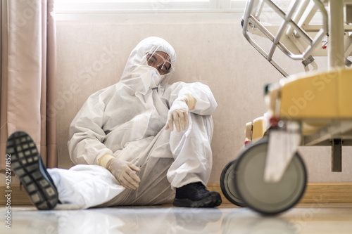 Asian man Doctor in protective hazmat PPE sad, tire and despair. Medical staff in clean suit. Male practitioner photo