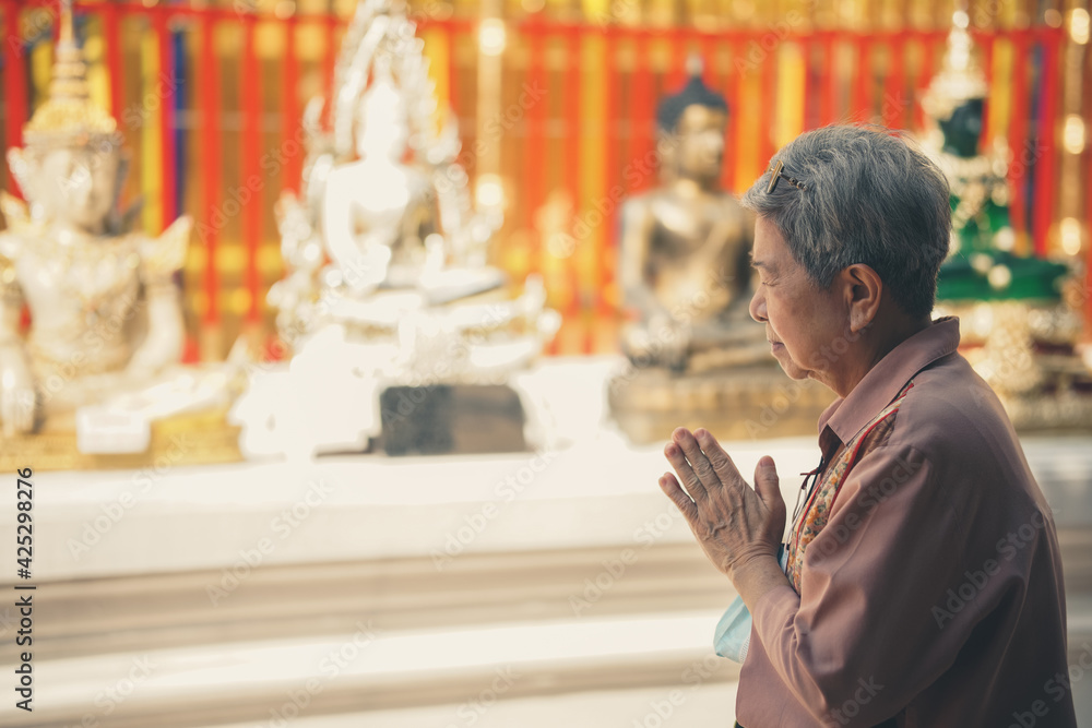 old asian senior woman traveler tourist praying at buddhist temple.
