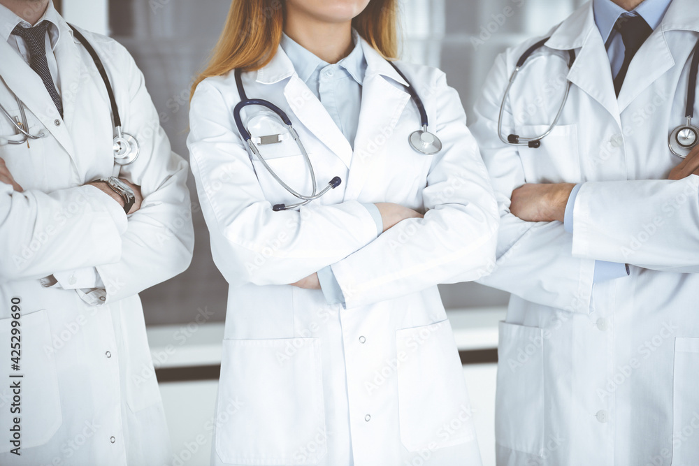 Group of unknown doctors standing as a team with arms crossed in hospital office, close-up. Medical help, insurance in health care and medicine concept Group of unknown doctors standing as a team with arms crossed in hospital office, close-up. Medical help, insurance in health care and medicine concept