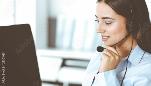 Wallpaper Mural Brunette female customer service representative in a headset is consulting clients online. Call center and business people concept Torontodigital.ca