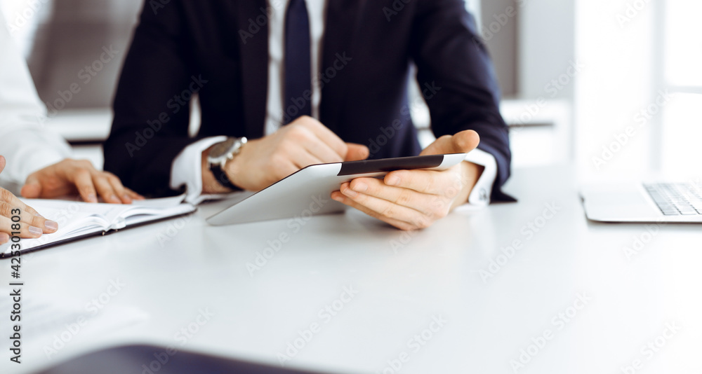 Unknown business people using tablet computer in modern office. Businessman or male entrepreneur is working with his colleague at the desk Unknown business people using tablet computer in modern office. Businessman or male entrepreneur is working with his colleague at the desk