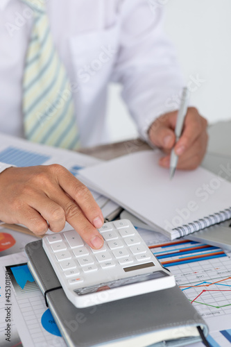 Close up Business man using calculator and laptop for do math finance on wooden desk, tax, accounting, statistics and analytical research concept