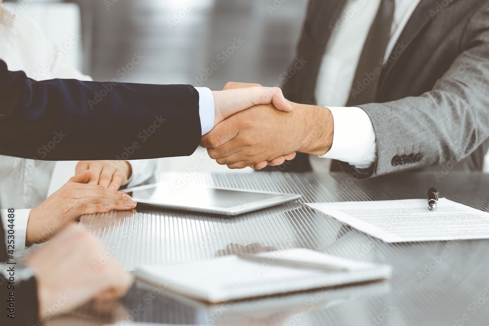 Handshake as successful negotiation ending, close-up. Unknown business people shaking hands after contract signing in modern office