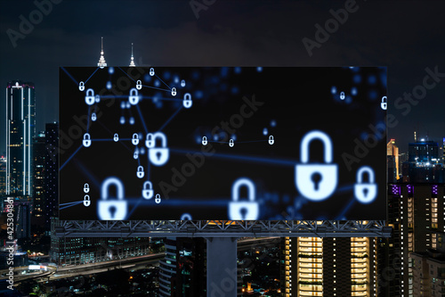 Padlock icon hologram on road billboard over panorama city view of Kuala Lumpur at night to protect business, Malaysia, Asia. The concept of information security shields.