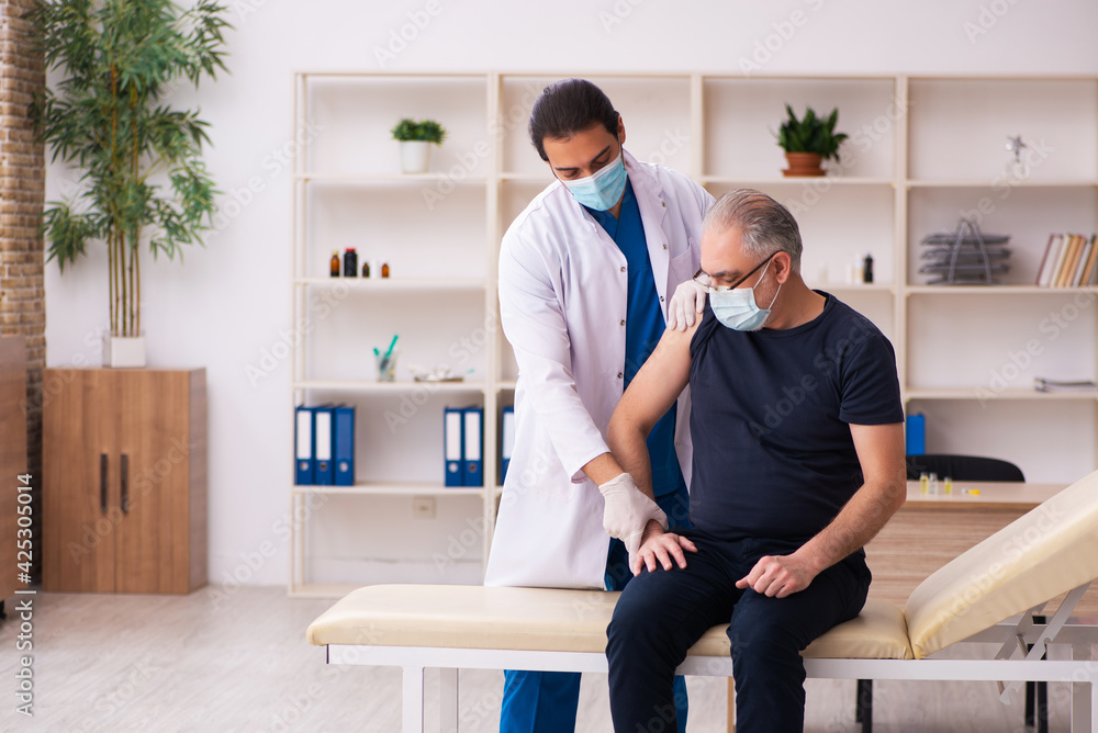 Obraz premium Old man visiting young doctor in covid-19 vaccination concept