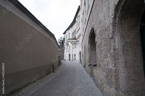 A deserted street in the old town with a stone pavement and arches in buildings.