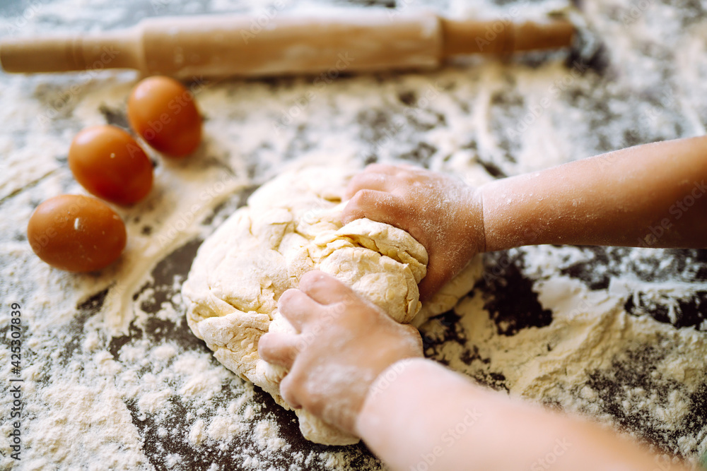Children hands kneading dough on wooden table. Easter baking preparation. Cookies for Christmas. Little chef preparing cake in kitchen. Children hands kneading dough on wooden table. Easter baking preparation. Cookies for Christmas. Little chef preparing cake in kitchen.