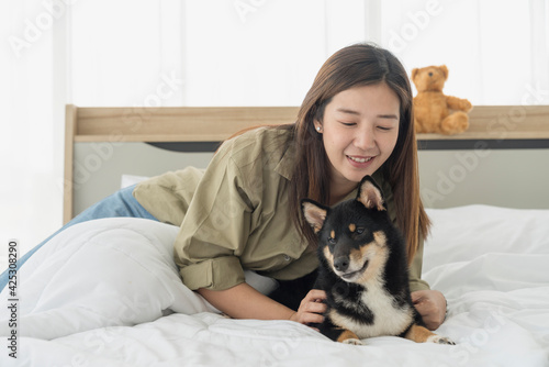 Young female playing with a Shiba Inu on the bed in the bedroom. Japanese dog.