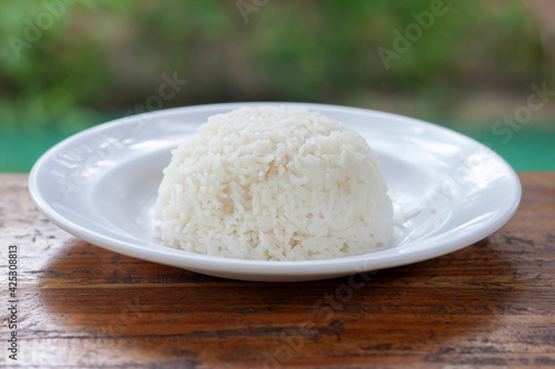 Ripe rice is the main food of Thailand in white plate placed on wooden background.