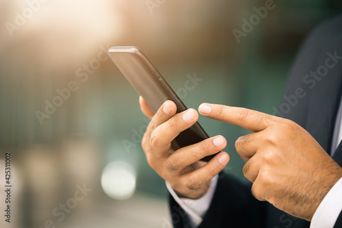Businessman hand holding using smartphone on urban city background.