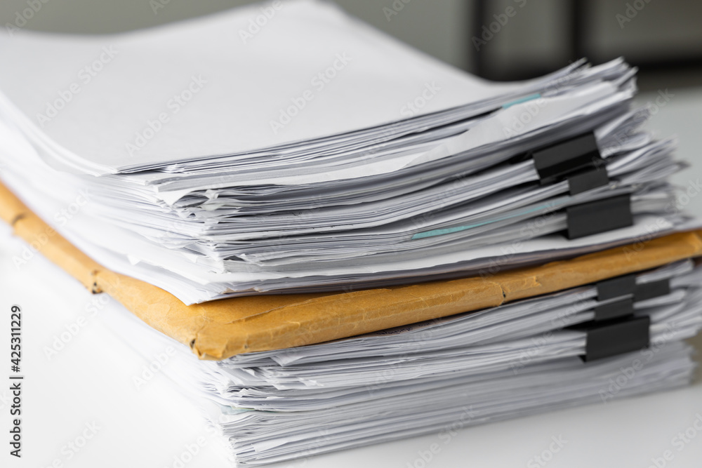 Piles of white papers work large piles of papers stacked together. On the desk in the office with black clip. Documents that are not finished. Business concept. Piles of white papers work large piles of papers stacked together. On the desk in the office with black clip. Documents that are not finished. Business concept.