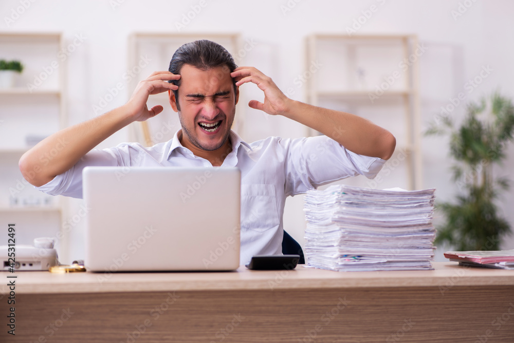 Young businessman employee unhappy with excessive work in the office Young businessman employee unhappy with excessive work in the office