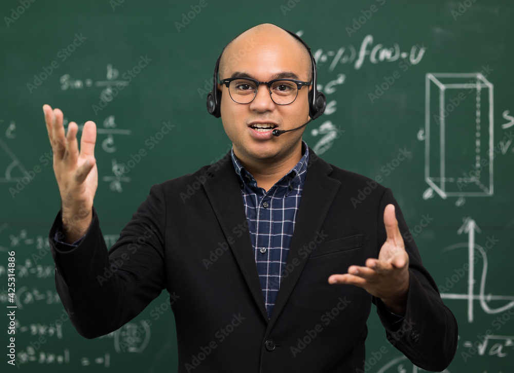 Young asian teacher man teaching video conference with student. Male Indian teacher training the mathematics in classroom from online course. He wearing small talk headset. Young asian teacher man teaching video conference with student. Male Indian teacher training the mathematics in classroom from online course. He wearing small talk headset.