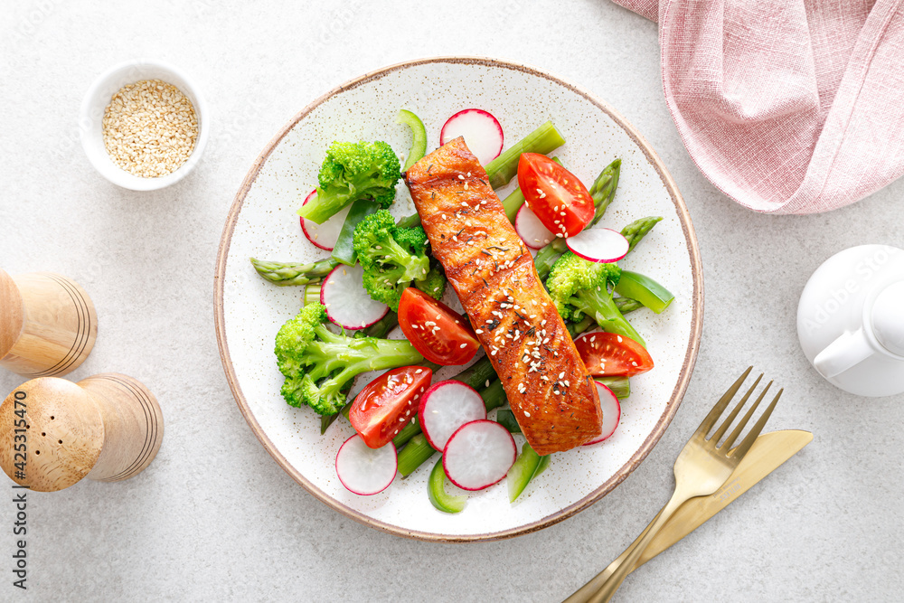 Salmon fish fillet grilled and vegetable salad with radish, tomato, green pepper, broccoli and asparagus. Salmon fish fillet grilled and vegetable salad with radish, tomato, green pepper, broccoli and asparagus.