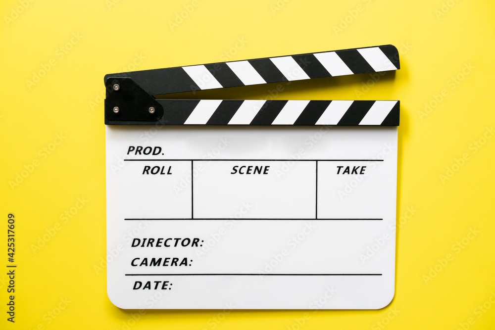movie clapper on yellow table background ; film, cinema and video photography concept