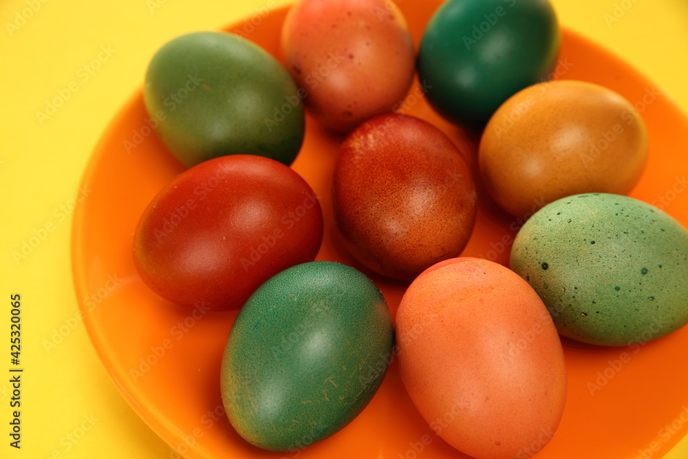 Colorful painted easter eggs on a plate, yellow background Colorful painted easter eggs on a plate, yellow background