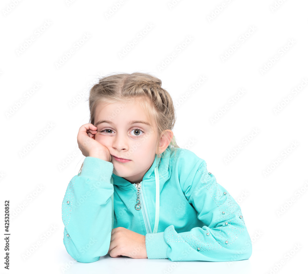 Little pensive girl sitting at the table and looking at the camera with her face on her hand. Isolated on white background. Little pensive girl sitting at the table and looking at the camera with her face on her hand. Isolated on white background.