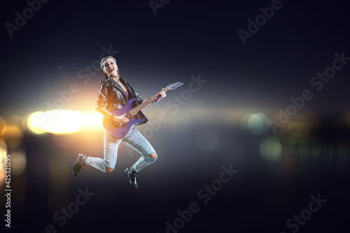 Young and beautiful rock girl playing the electric guitar