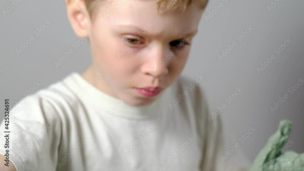 a seven year old boy, soiled in clay, is concentrating on making a clay product on a potter's wheel. close-up. Horizontal. a seven year old boy, soiled in clay, is concentrating on making a clay product on a potter's wheel. close-up. Horizontal.