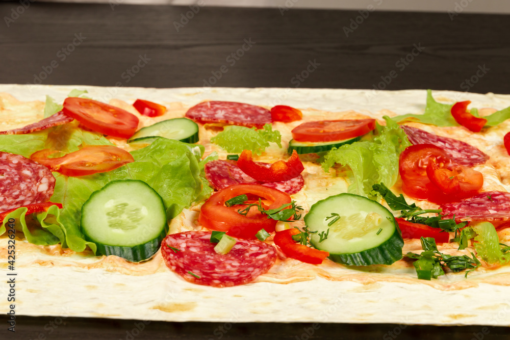 ingredients for shawarma are laid out on a thin pita bread. tomatoes, greens, salami, cheese, cucumber and lettuce close-up ingredients for shawarma are laid out on a thin pita bread. tomatoes, greens, salami, cheese, cucumber and lettuce close-up
