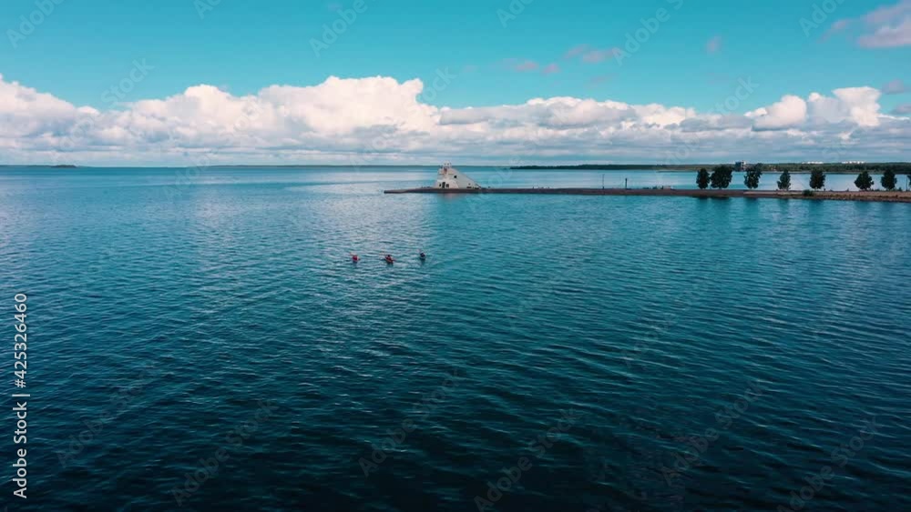 Aerial view of kayaks on the Gulf of Bothnia, Nallikari lighthouse background, summer in Oulu, Finland - Tracking, drone shot Aerial view of kayaks on the Gulf of Bothnia, Nallikari lighthouse background, summer in Oulu, Finland - Tracking, drone shot