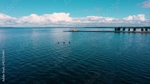 Aerial view of kayaks on the Gulf of Bothnia, Nallikari lighthouse background, summer in Oulu, Finland - Tracking, drone shot photo