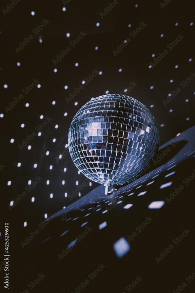 Illuminated by sun light silver disco mirror ball. Dark black