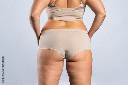 Overweight woman with fat hips and buttocks, obesity female body on gray background © staras