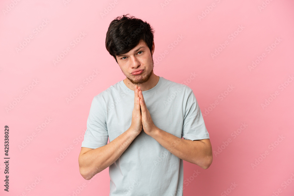 Young Russian man isolated on pink background keeps palm together. Person asks for something Young Russian man isolated on pink background keeps palm together. Person asks for something