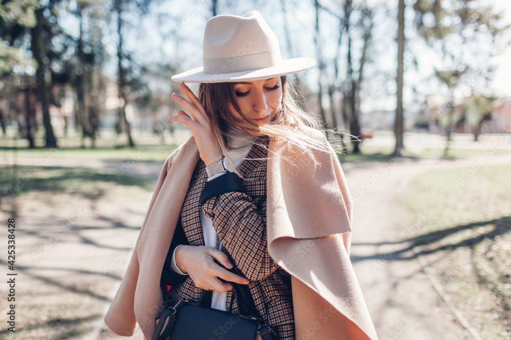 Portrait of fashionable woman wearing stylish clothes and accessories in park. Spring female outfit.