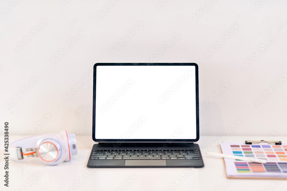Tablet blank white screen is placed at the work desk with color swatch at the office. Mock up. Tablet blank white screen is placed at the work desk with color swatch at the office. Mock up.