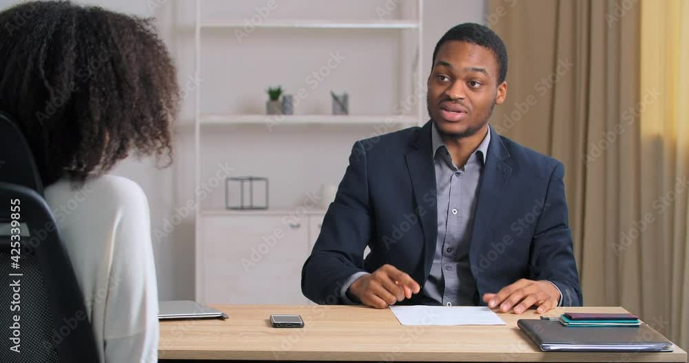Emotional afro american business man worker sitting at office feeling angry upset actively gesticulating explaining speaks loudly expresses opinion idea of sartup project for unmanageable female boss Emotional afro american business man worker sitting at office feeling angry upset actively gesticulating explaining speaks loudly expresses opinion idea of sartup project for unmanageable female boss