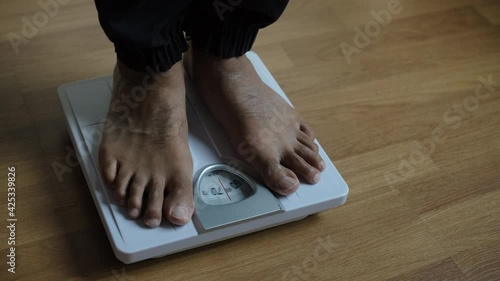 Asians foot man with body weight scales for measure weight loss.Weighing scale to healthy slimming concept.medium long shot panning dolling shift focus dolly slider for slow motion