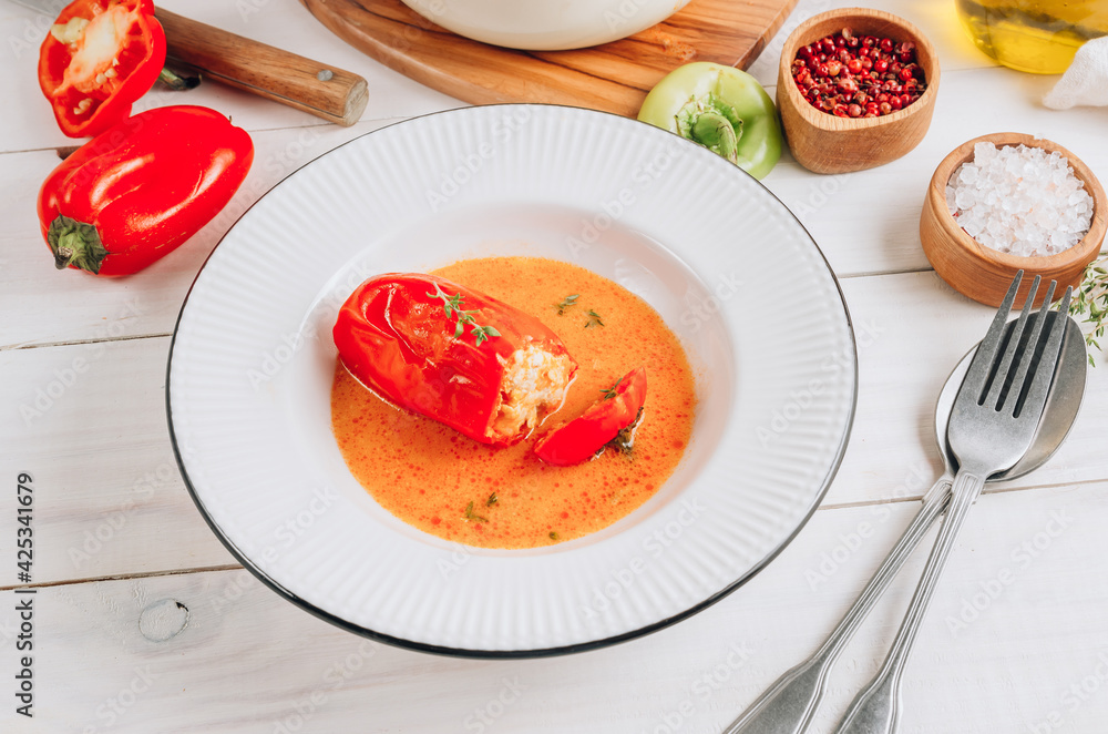 Pepper stuffed with minced chicken meat and rice in a white plate on a white wooden table. Pepper stuffed with minced chicken meat and rice in a white plate on a white wooden table.