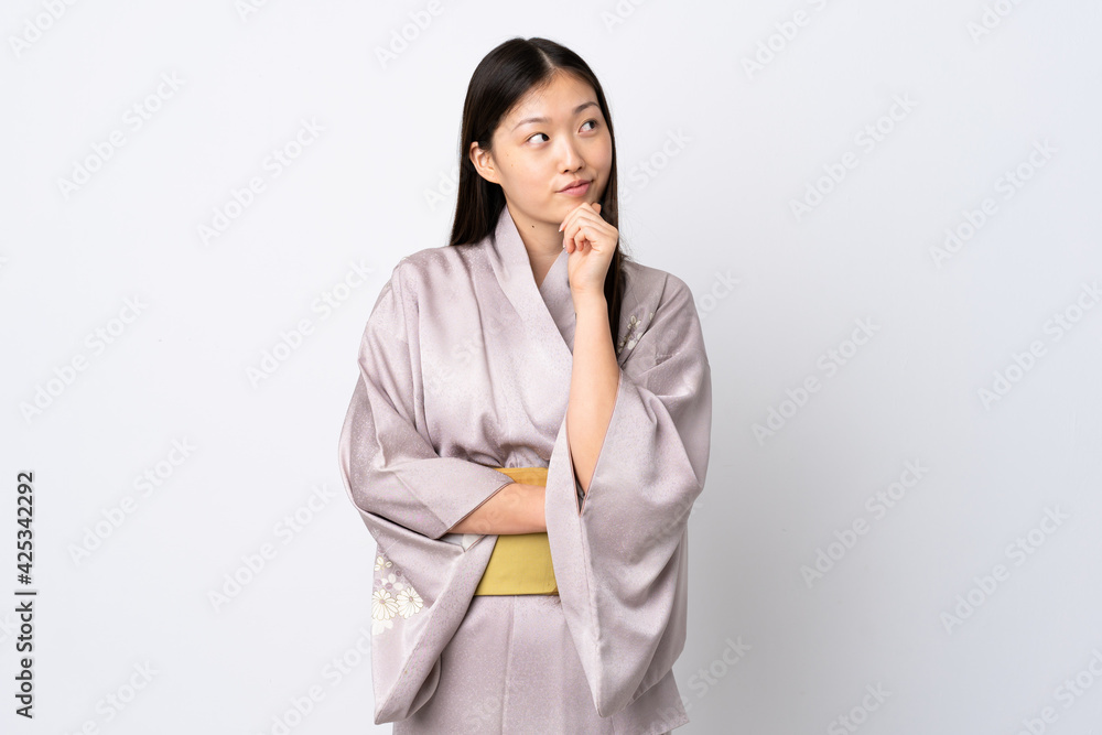 Young Chinese girl wearing kimono over isolated background thinking an idea while looking up Young Chinese girl wearing kimono over isolated background thinking an idea while looking up