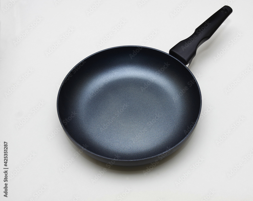 Modern black frying pan for induction hobs on a white background. Non-stick coating. Selective focus with copy space. Modern black frying pan for induction hobs on a white background. Non-stick coating. Selective focus with copy space.