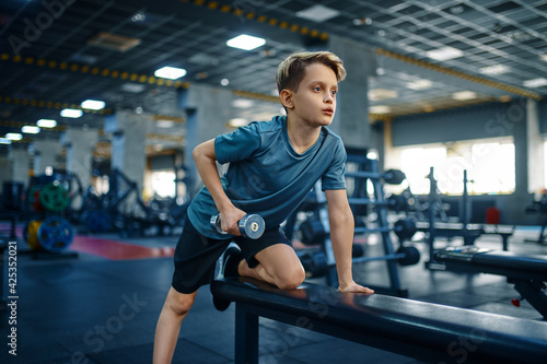 Youngster doing exercise with dumbbell on bench