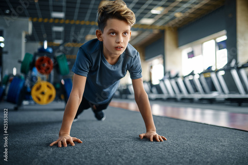 Boy doing push up exercise in gym, front view