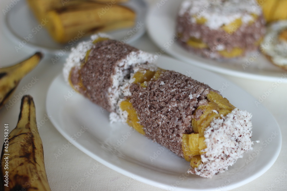 Steamed finger millet flour cake with a generous layer of fresh coconut in between. Locally known as Ragi puttu. Served with steamed plantain. Steamed finger millet flour cake with a generous layer of fresh coconut in between. Locally known as Ragi puttu. Served with steamed plantain.