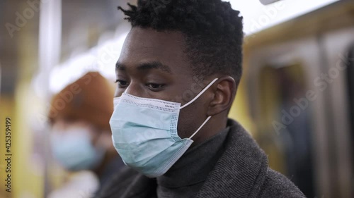 Black man standing at metro subway wearing covid-19 face mask during pandemic photo