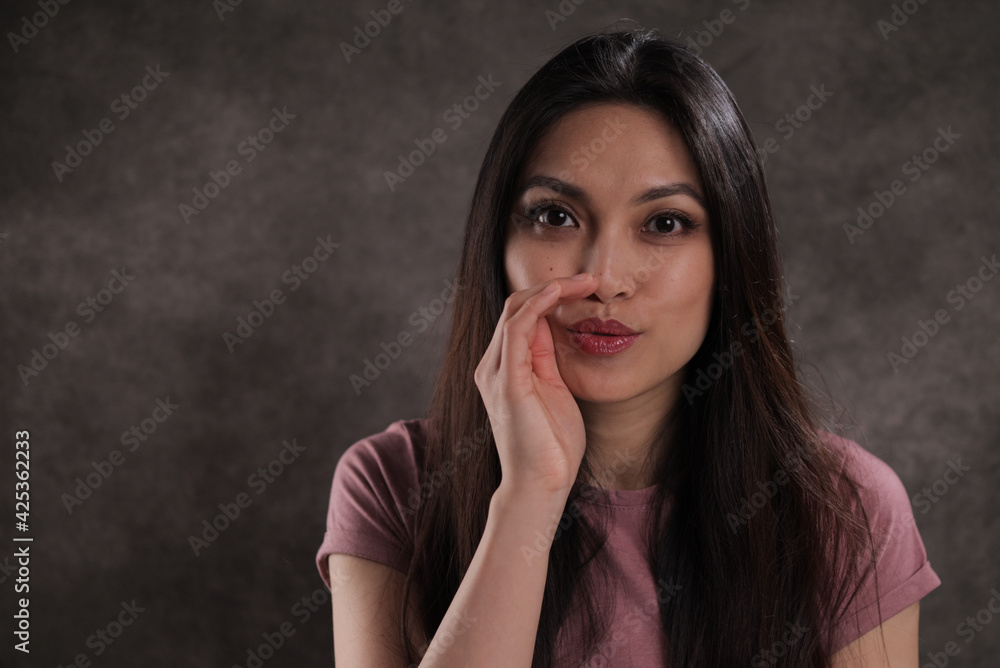 Young woman whispers something to the camera - studio photography Young woman whispers something to the camera - studio photography