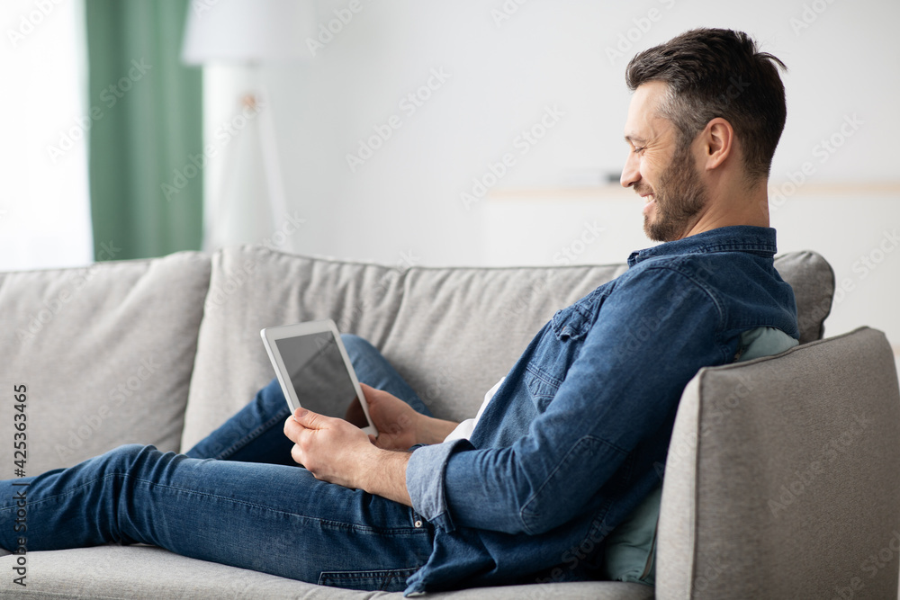 Smiling bearded man using digital tablet with empty screen Smiling bearded man using digital tablet with empty screen