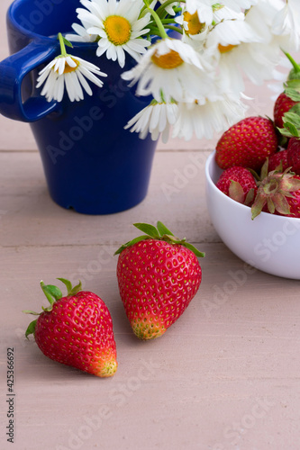 Vertical composition of strawberriies and chamomile flowers photo