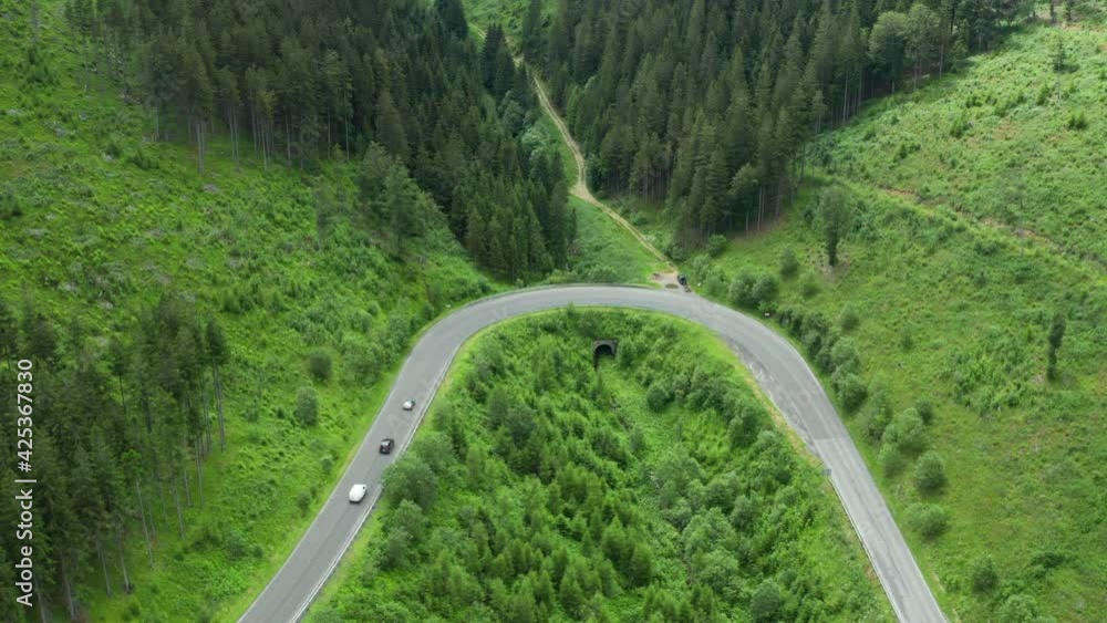 Aerial view of serpentine road with driving cars in mountains with high green trees. Aerial view of serpentine road with driving cars in mountains with high green trees.