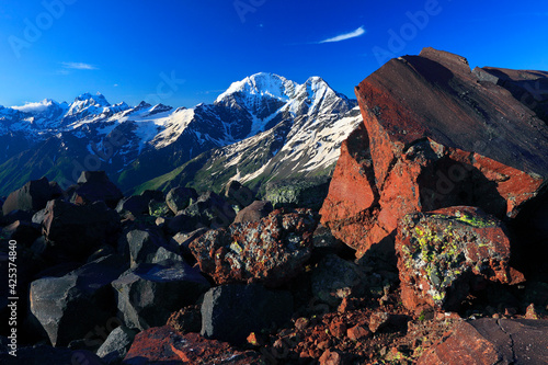 Elbrus region, Garabashi station, Kabardino-Balkaria, Russia. Landscape with rock formation, cloudy sky and Elbrus mountains in the distance. photo