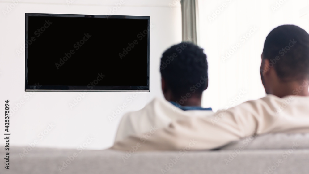 Black couple watching TV with mockup, sitting on couch Black couple watching TV with mockup, sitting on couch