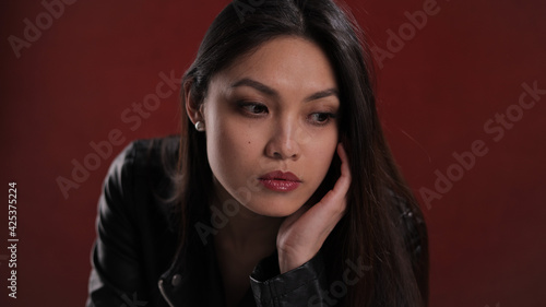 Young thoughtful woman against a red background - studio photography