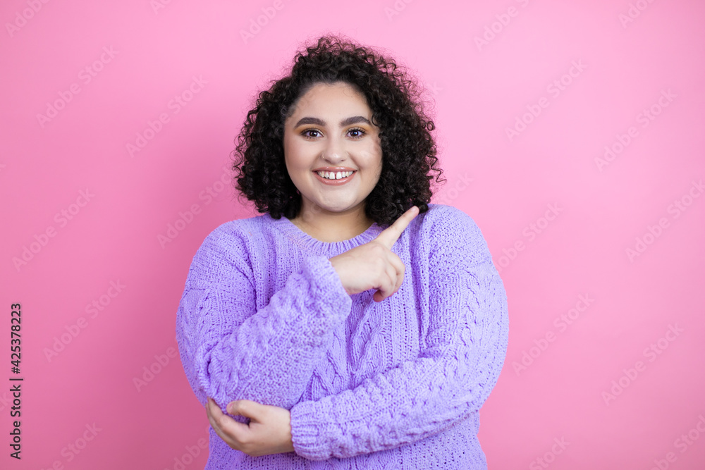 Young beautiful woman wearing casual sweater over isolated pink background smiling and pointing with hand and finger to the side Young beautiful woman wearing casual sweater over isolated pink background smiling and pointing with hand and finger to the side